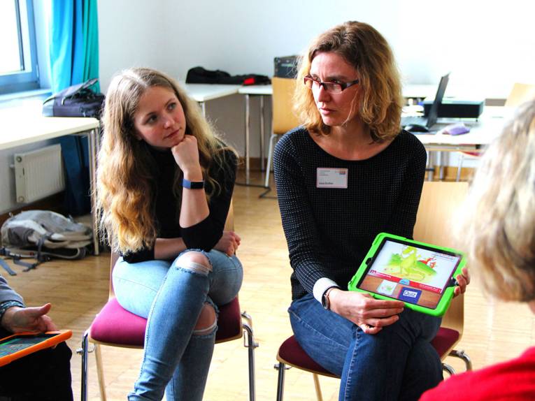 Lena Grether erklärt an einem Kinder-Tablet eine App zur Leseförderung.